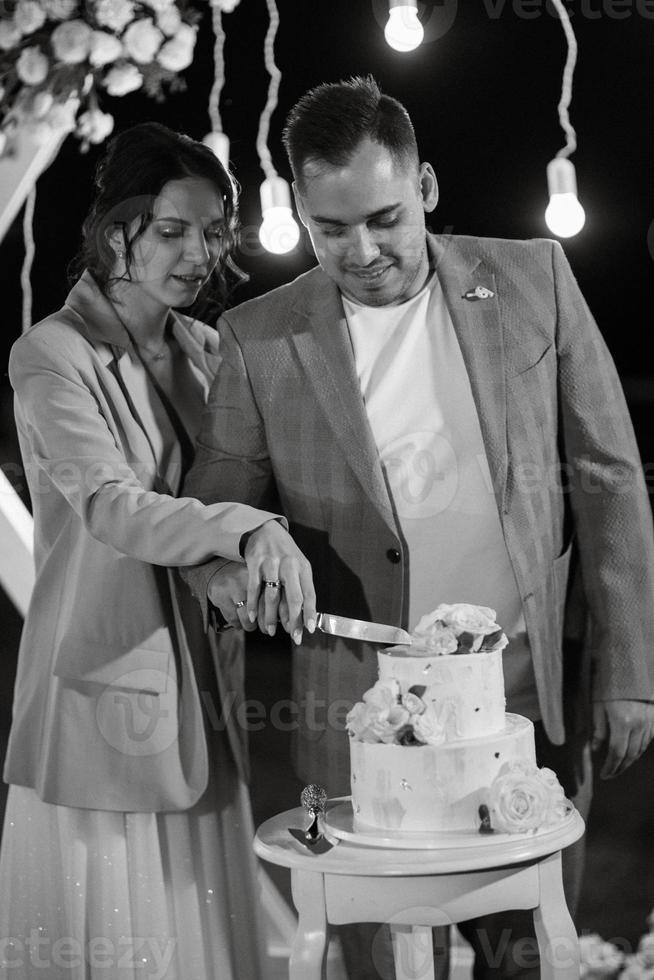 los recién casados felizmente cortan y prueban el pastel de bodas foto