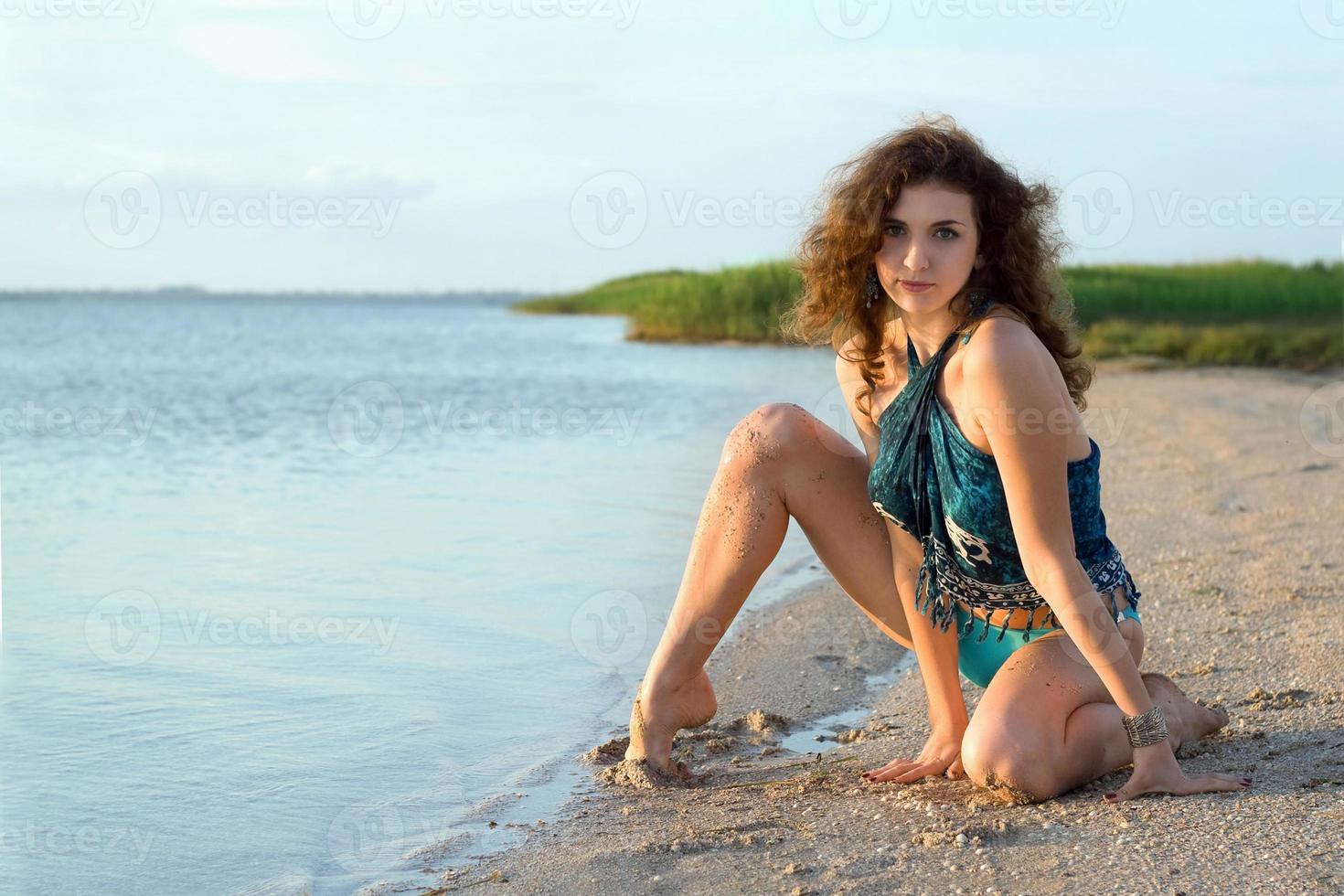 Beautiful young woman sitting on the bay photo