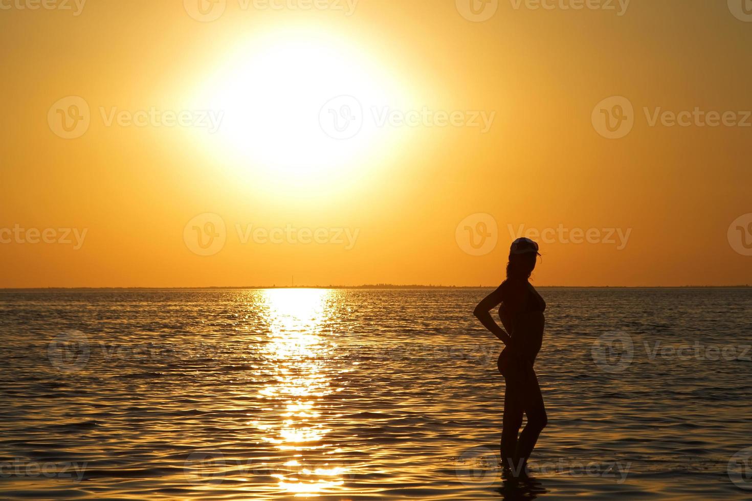 Silhouette of the young woman on a sea bay on a sunset photo