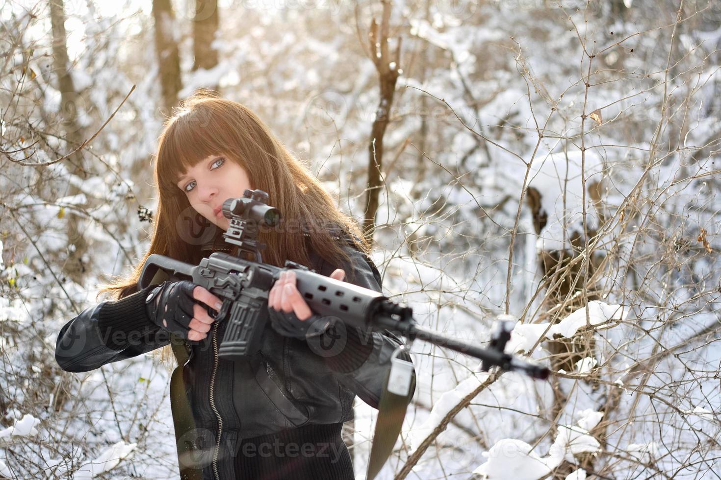 chica morena apuntando un arma foto