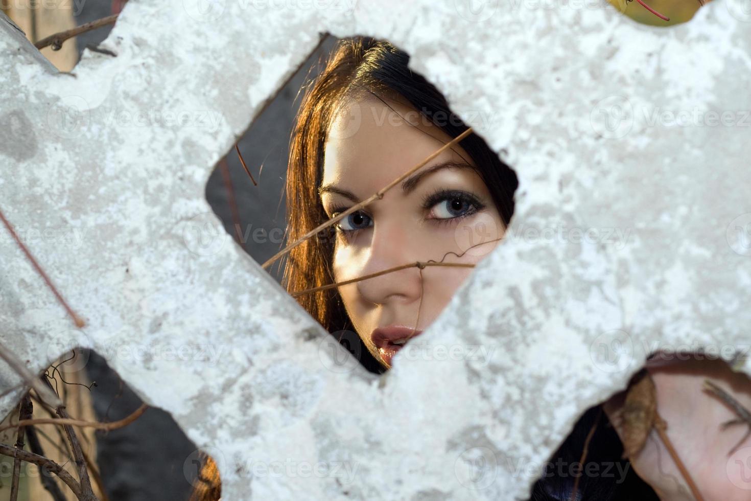 The young woman looks through a fence photo