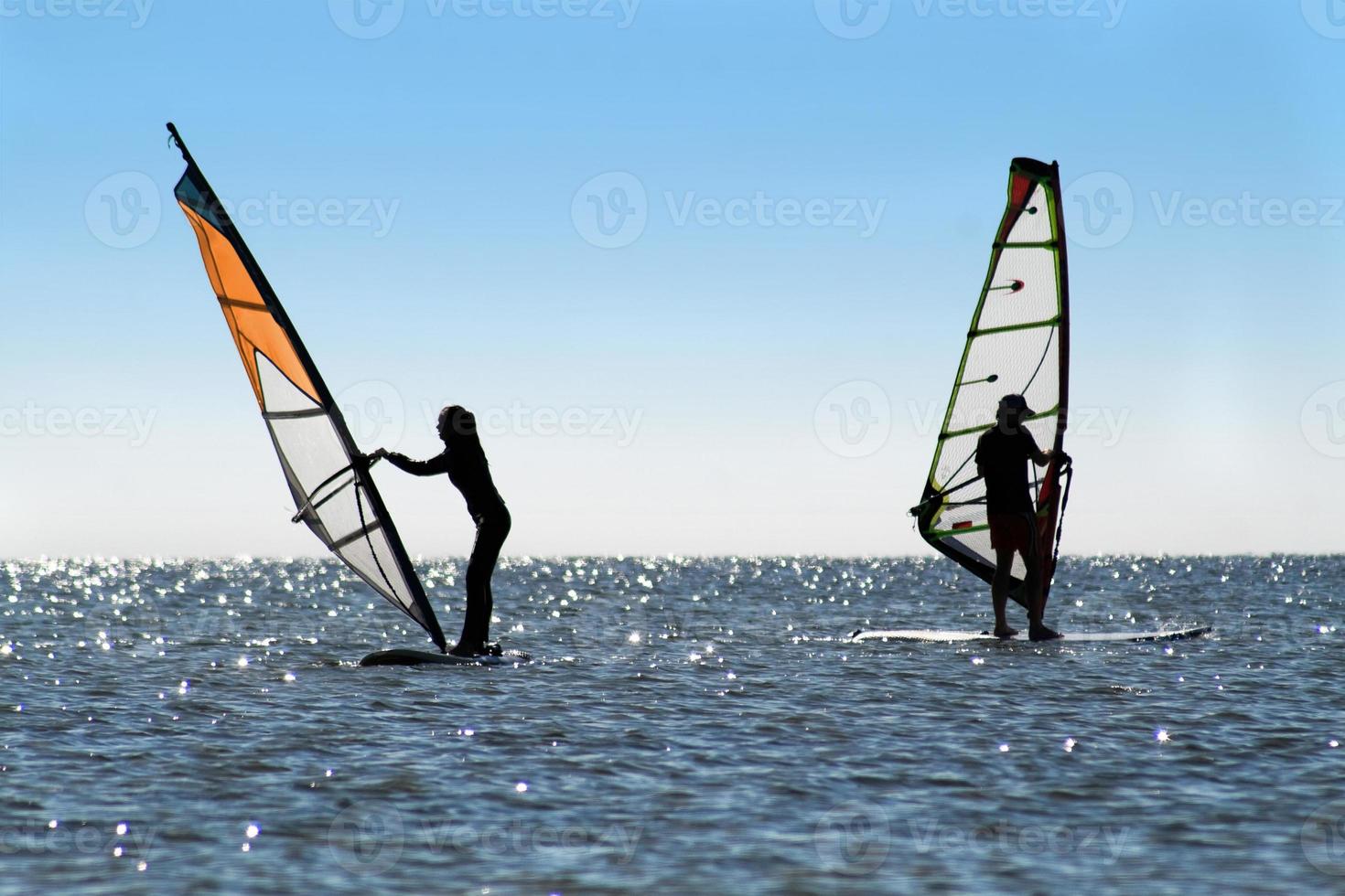 Silhouette of a two windsurfers photo