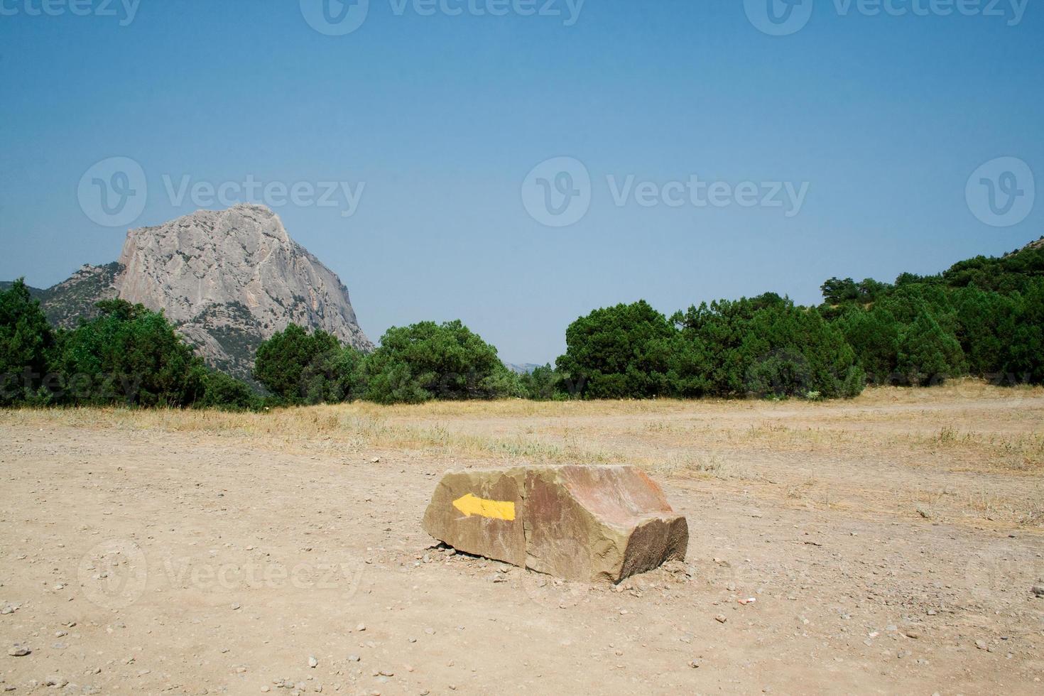 Yellow arrow on a stone, specifying a direction in mountains photo