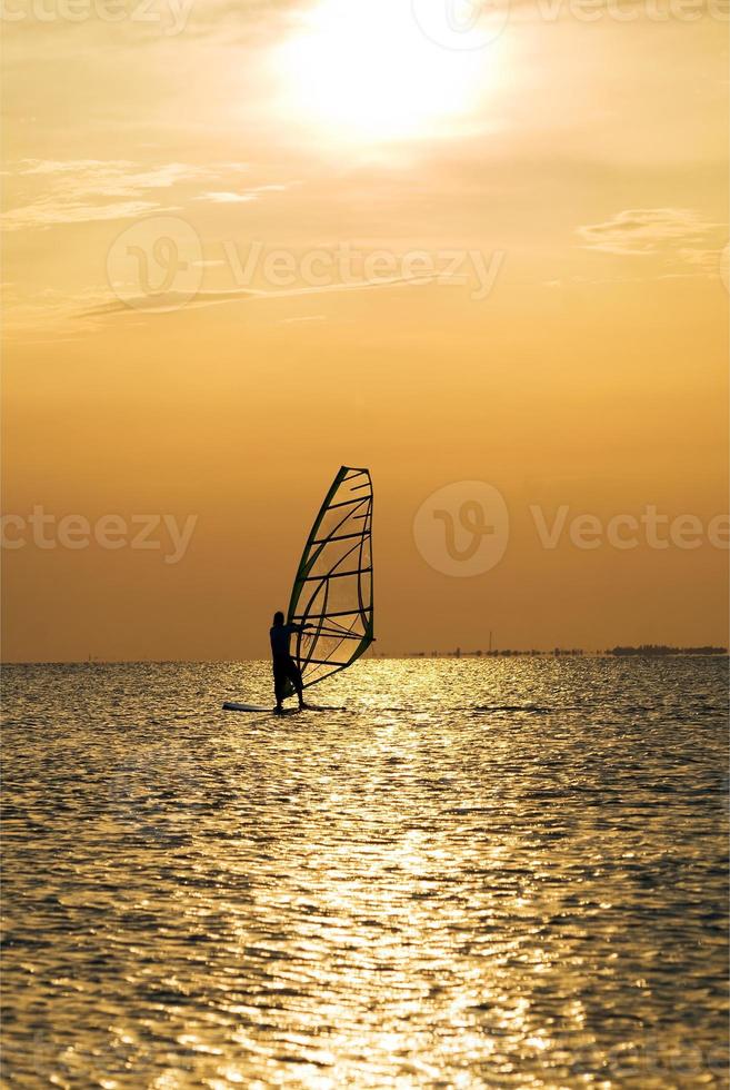 Silhouette of a windsurfer on a sunset photo