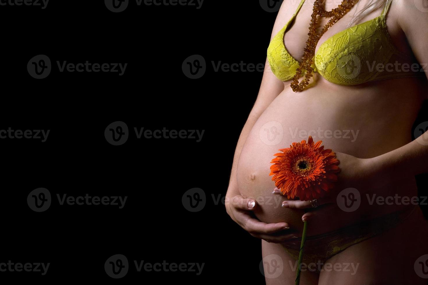 Belly of a pregnant young woman with flower. Isolated photo