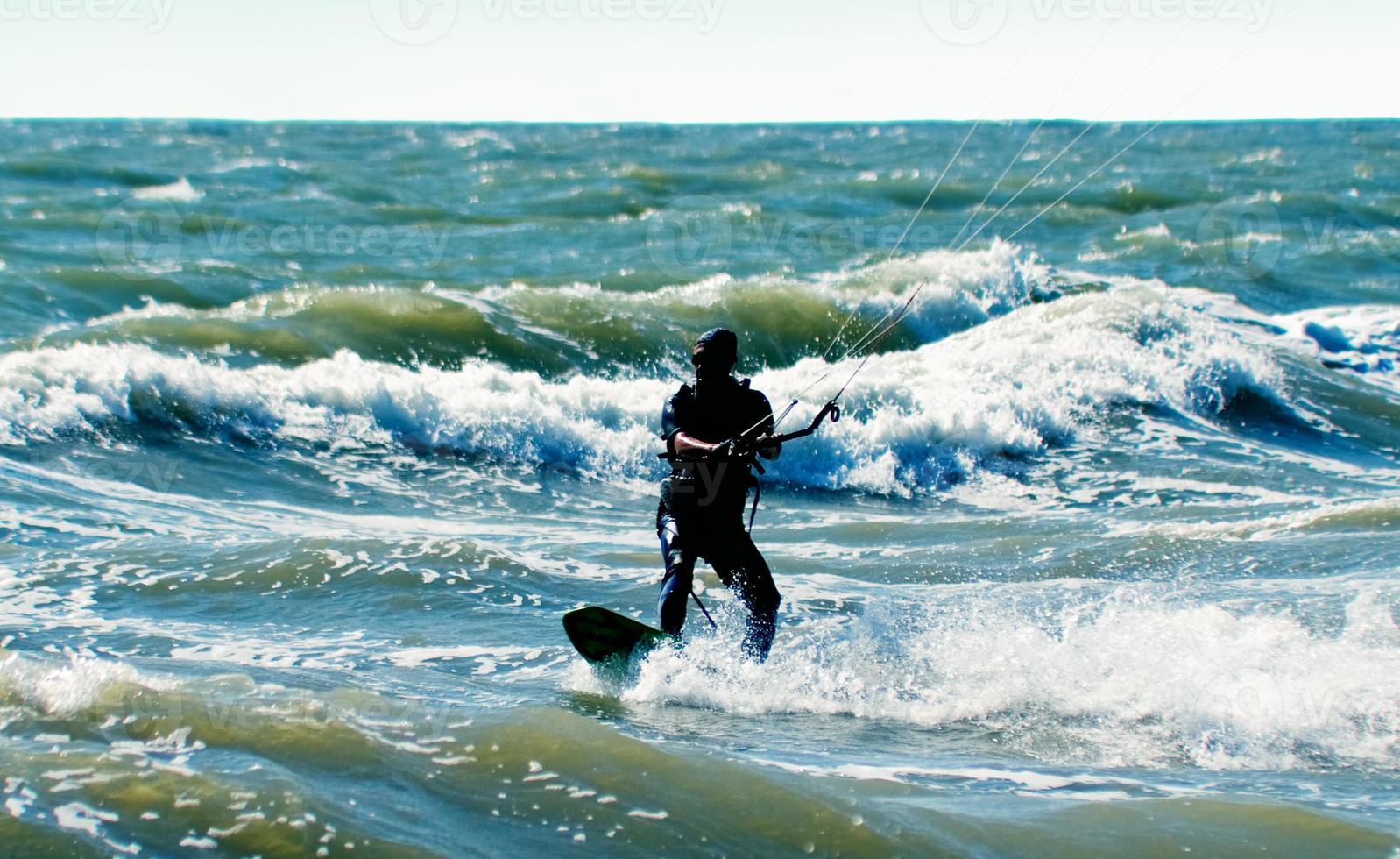 Silhouette of a kitesurfer on waves of a sea photo