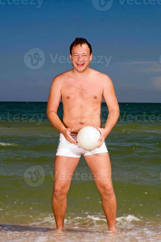 young man holding a ball on the beach photo