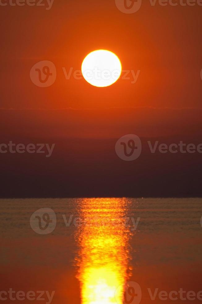 puesta de sol roja sobre la superficie del mar foto