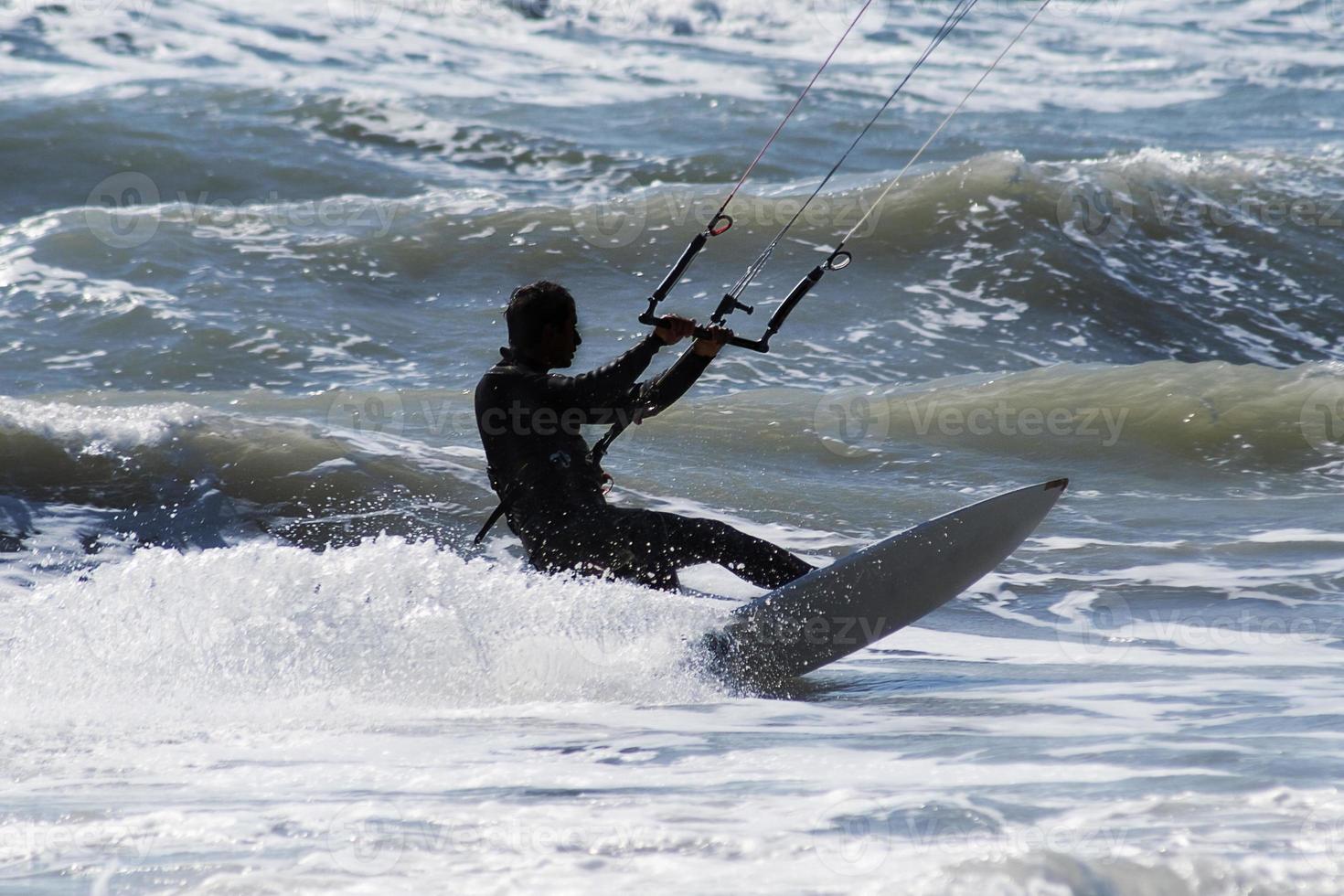 Silhouette of kite surfer jumping over the waves photo