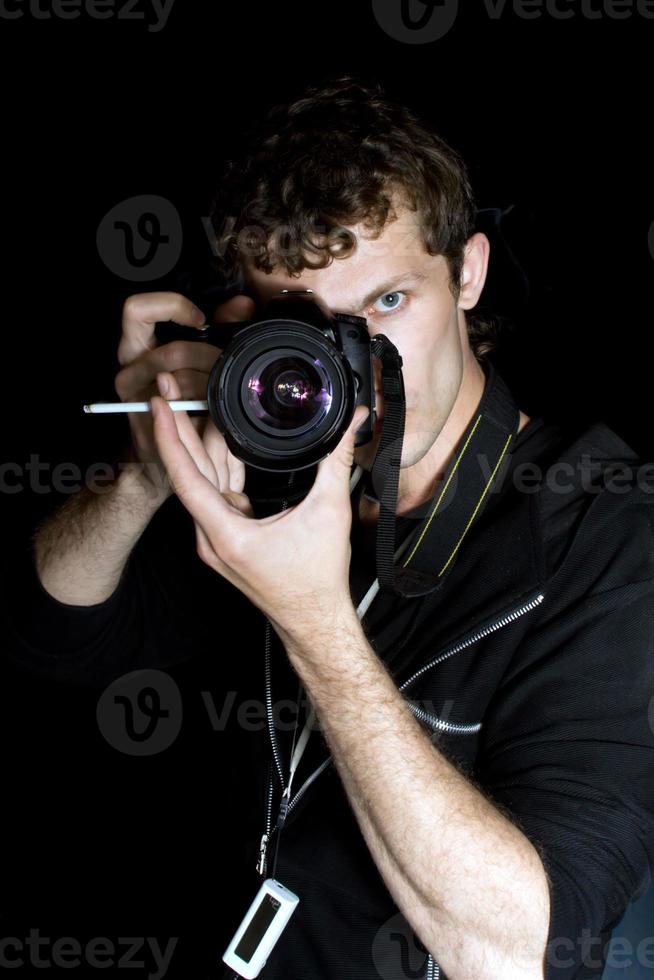 The young man - photographer behind work. Isolated on a black background 2 photo