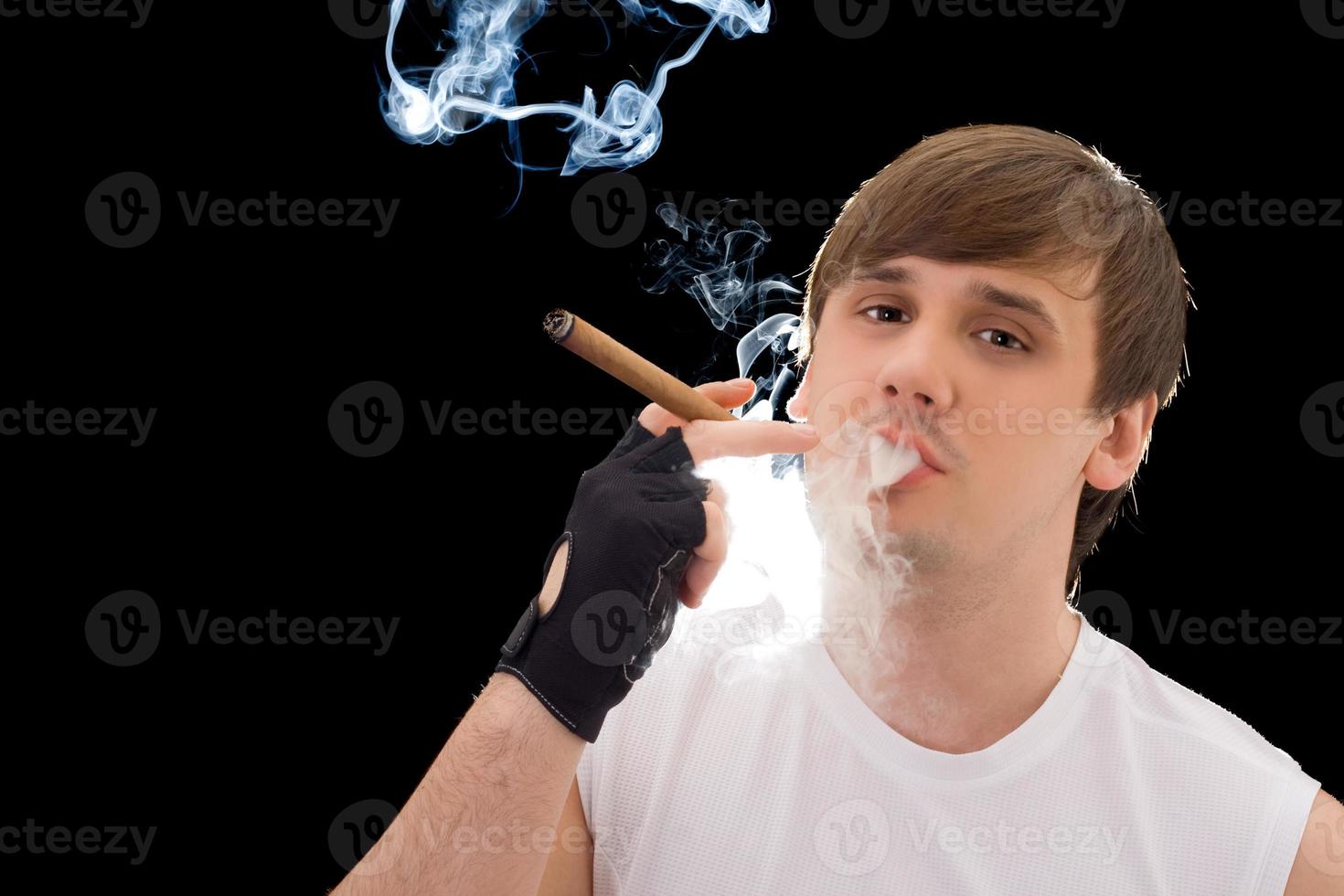 joven fumando un cigarro. aislado en negro foto