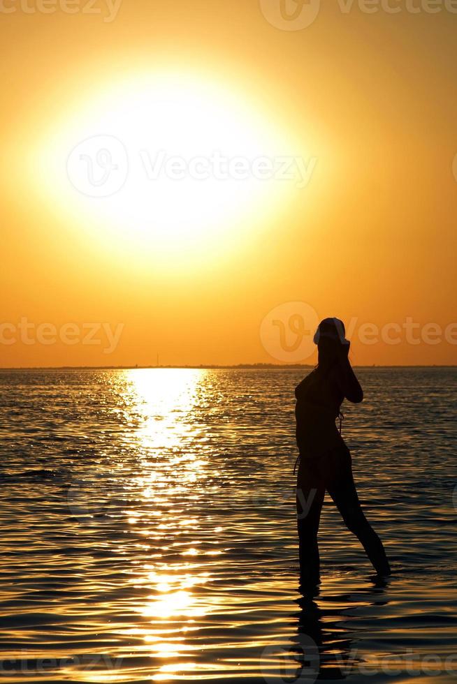 silueta de la joven en una bahía al atardecer foto