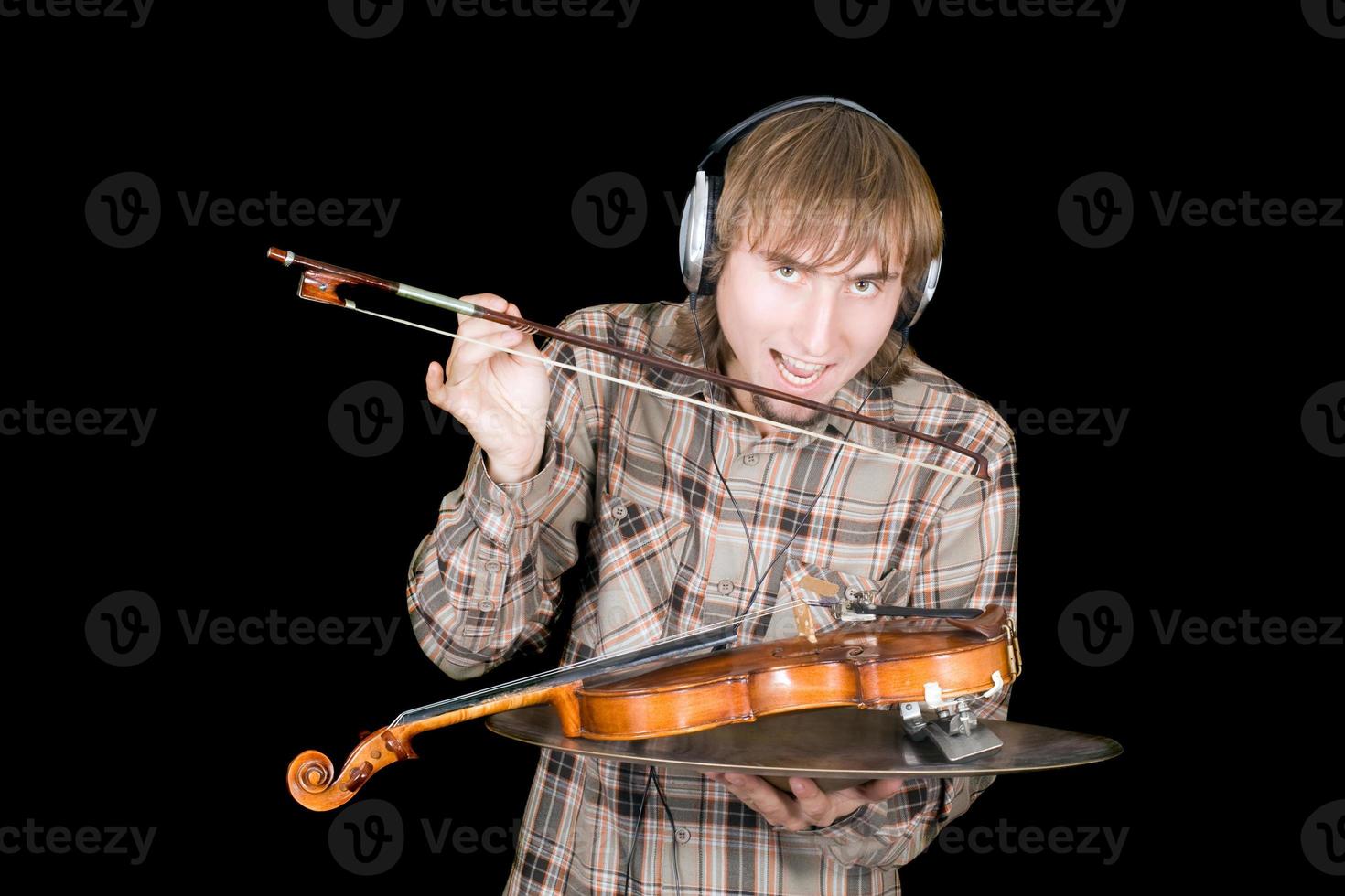 The young man in ear-phones eats a violin photo