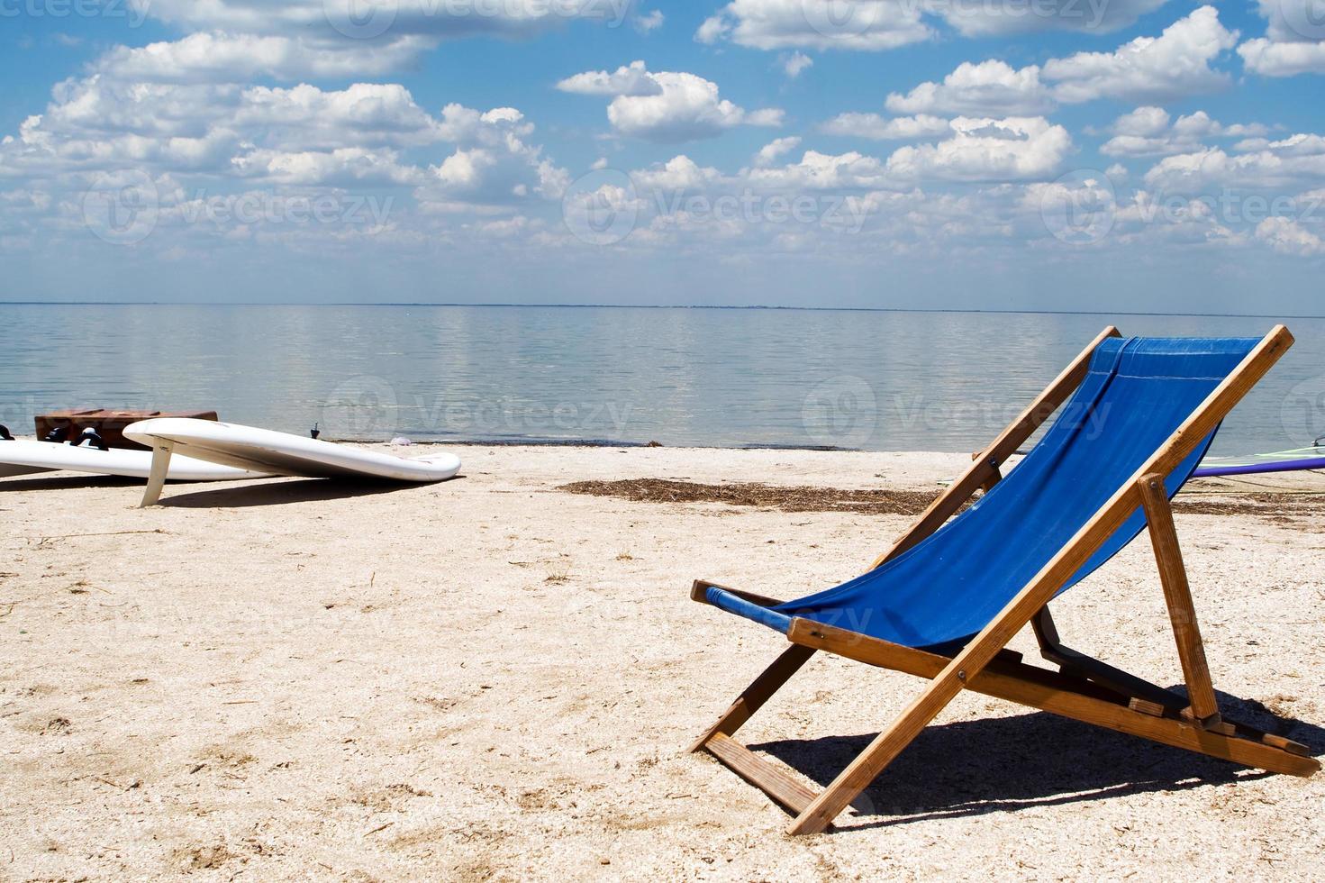 Chair on a beach against a gulf and clouds photo