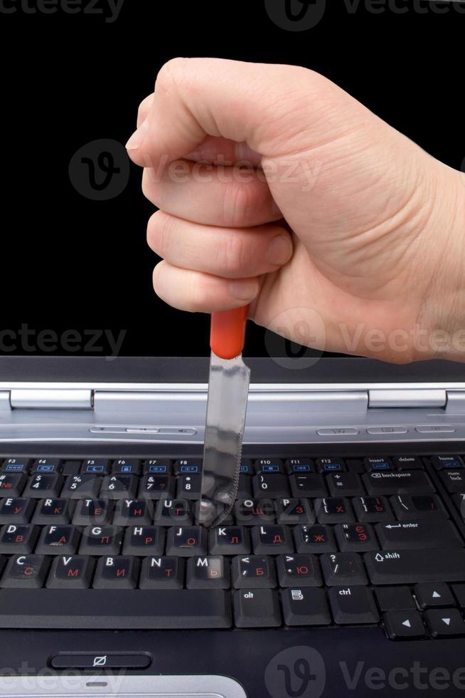 mano con un cuchillo en el teclado del portátil foto