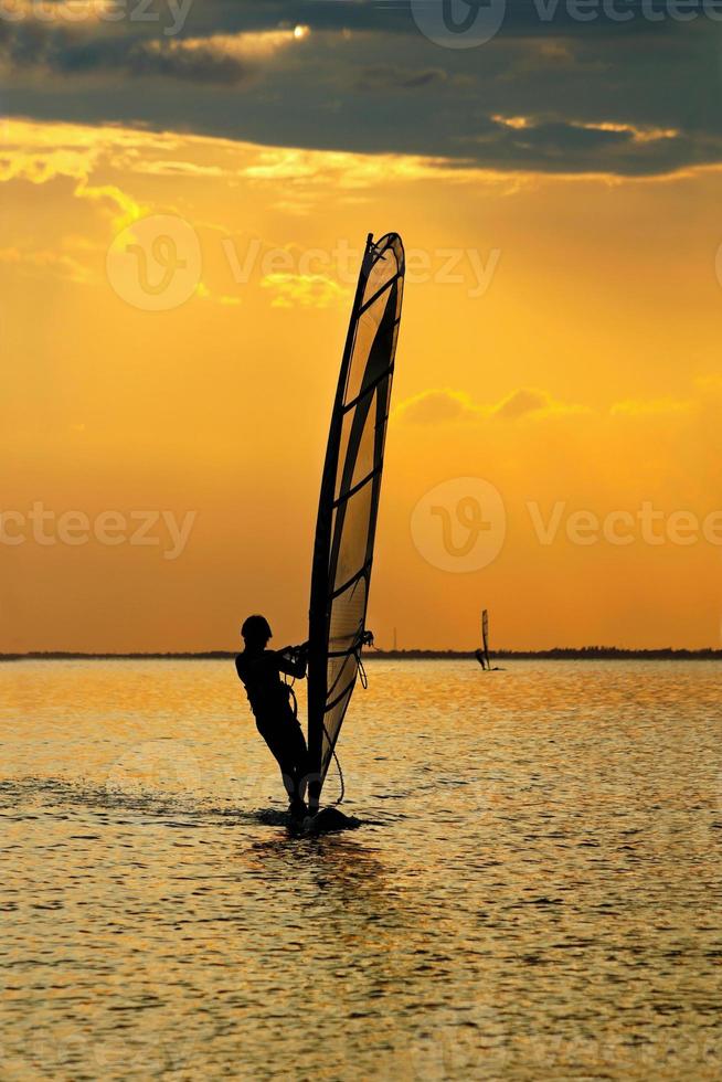 hombre windsurfista sobre la puesta de sol foto