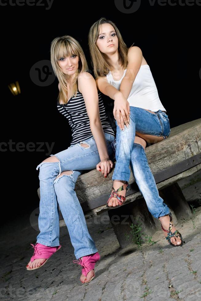 Two pretty girls sitting on a stone photo