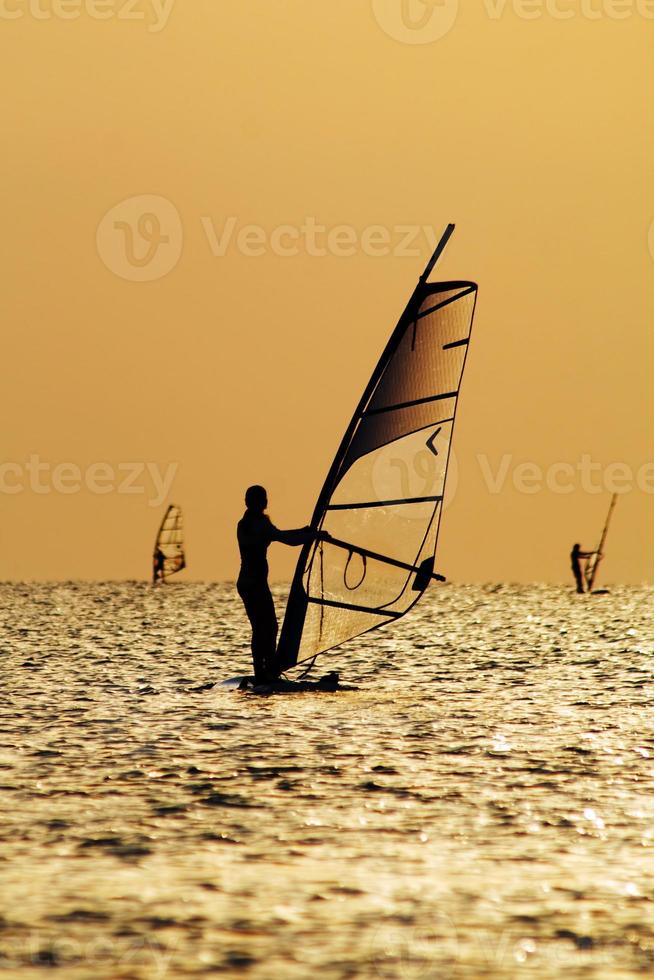 Silhouettes of a windsurfers on waves of a gulf photo