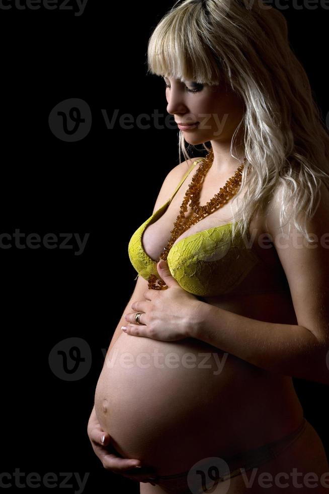 Pregnant young woman in yellow lingerie. Isolated photo