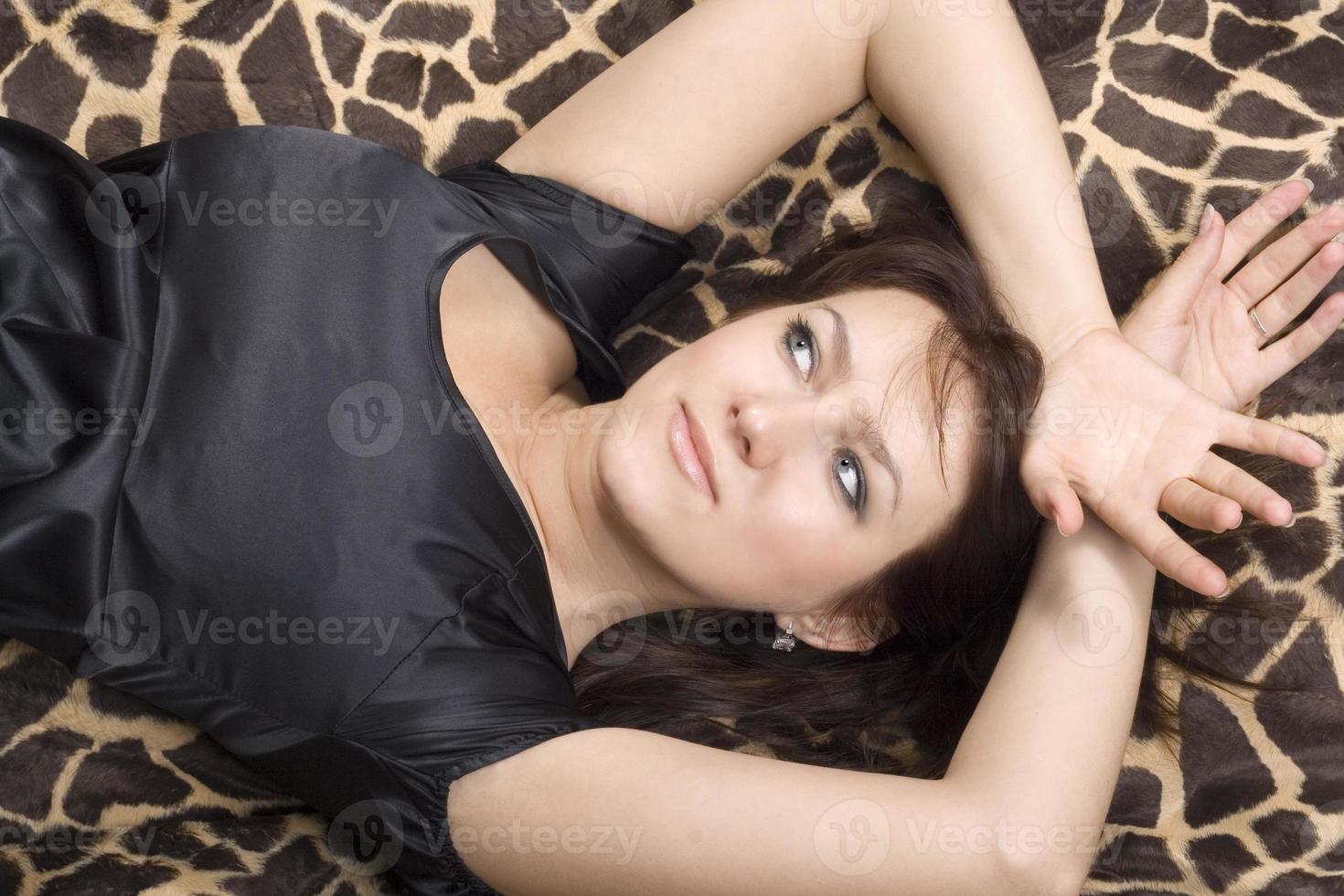 young beauty woman in black dress lies on a bed photo