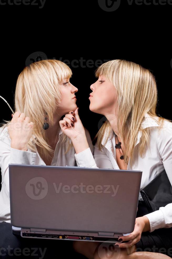 Two kissing businesswomen with laptop. Isolated on black photo