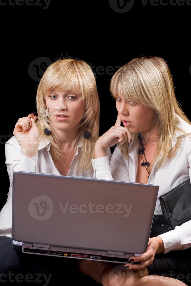 Two young businesswomen sitting with laptop. Isolated photo