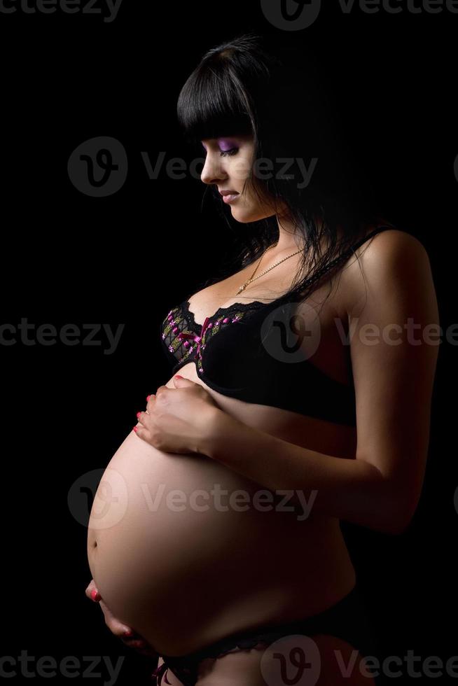 Pregnant brunette in lingerie. Isolated photo