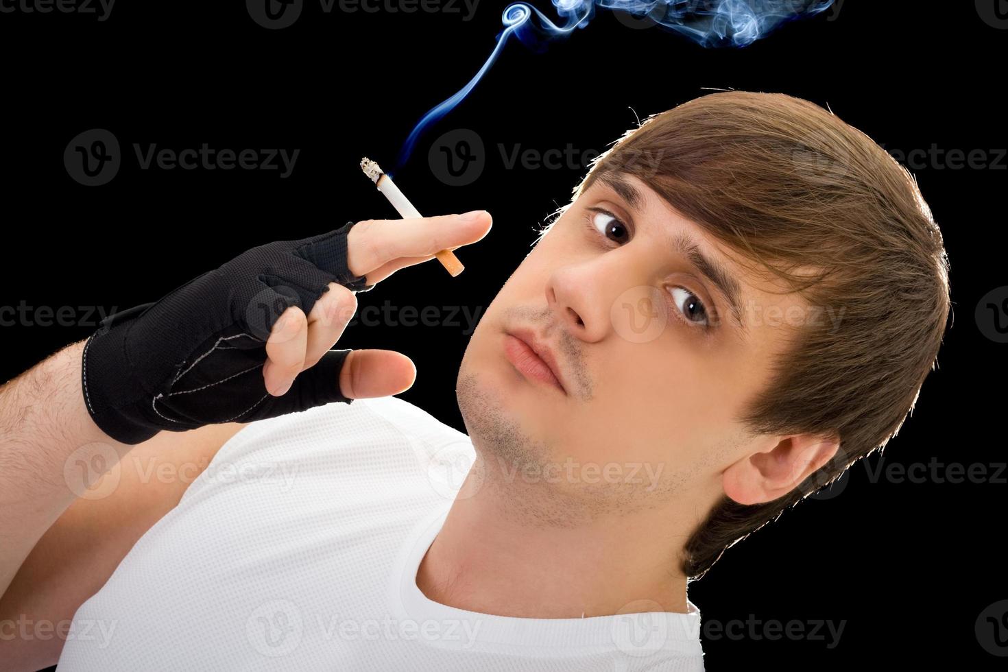 Young  man with a cigarette. Isolated on black photo