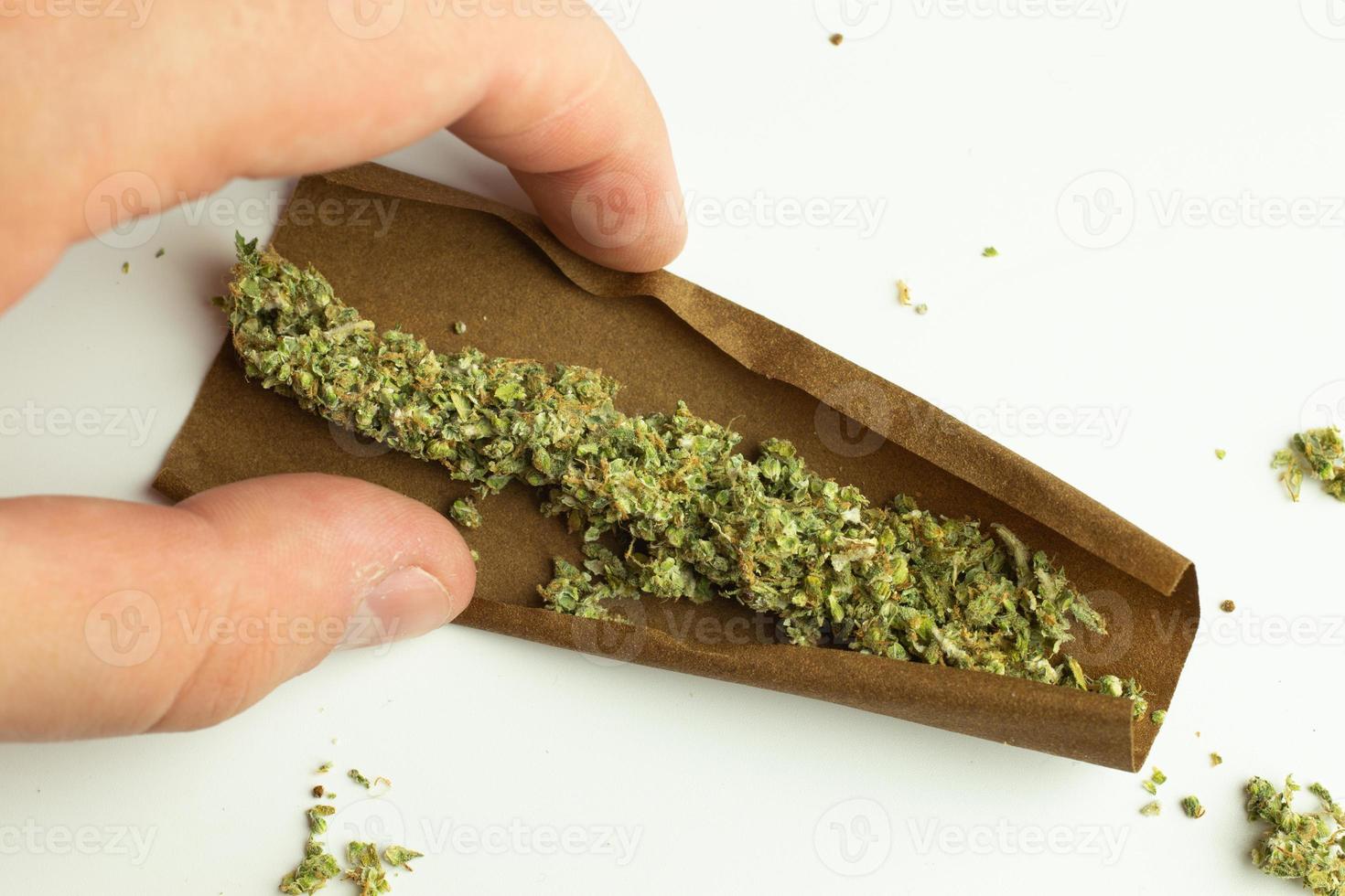 Blunt of weed on white background top view. Cannabis rolled in paper for smoking. Recreational drug use photo