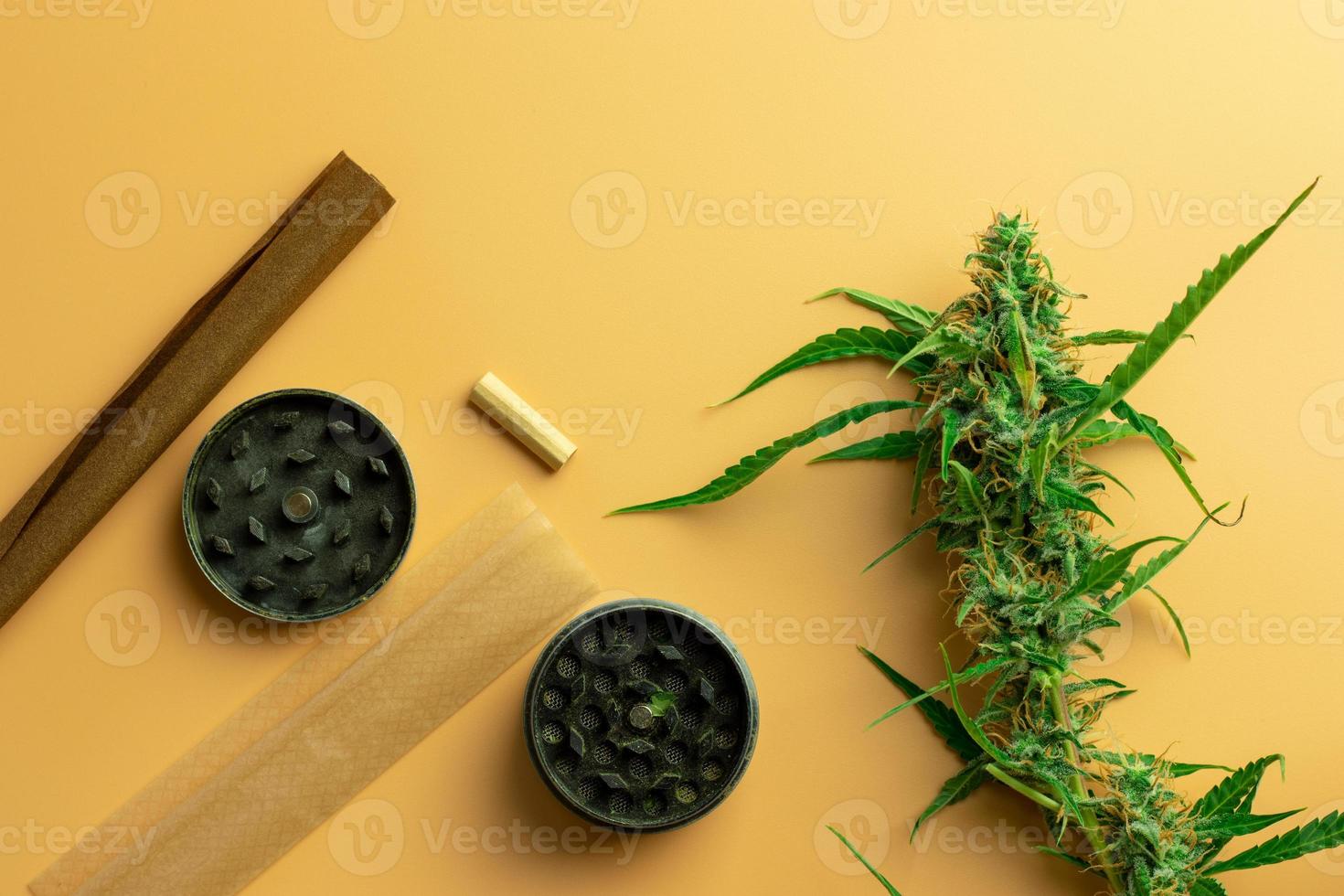 Cannabis and weed industry business. Marijuana accessories use concept. Grinder, paper and blunt with hemp bud on desk photo