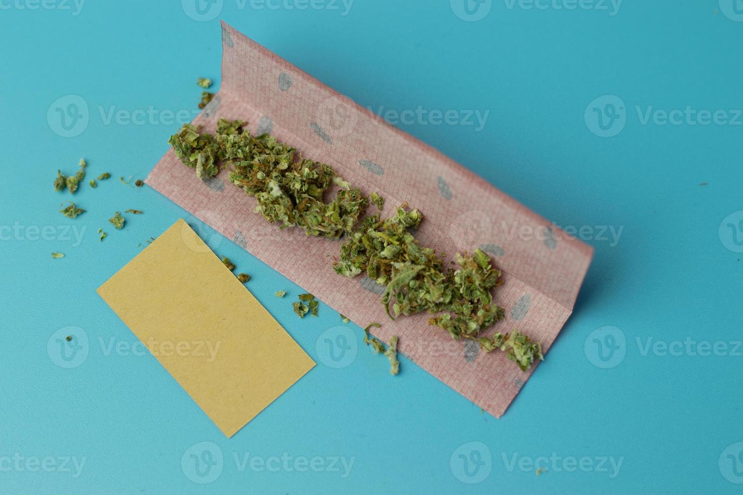 papel común para rollo de cannabis en la vista superior de fondo azul, accesorio para fumar marihuana foto