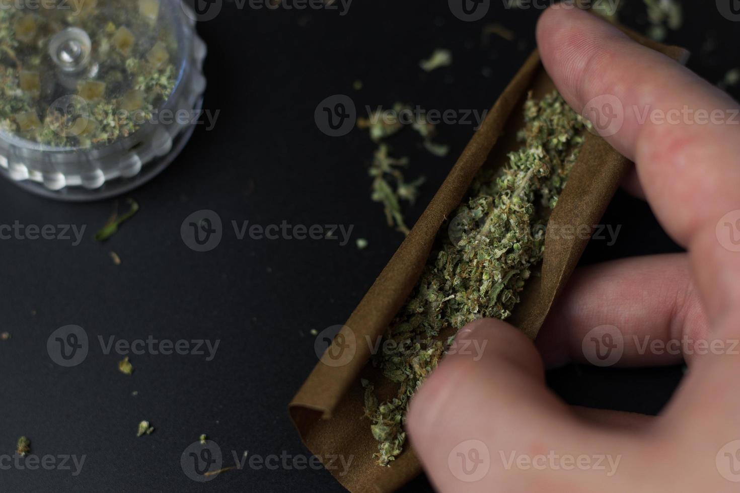 Hand holds cannabis in blunt roll paper. Marijuana medical and recreational use concept. Selfcare with herbal THC weed photo