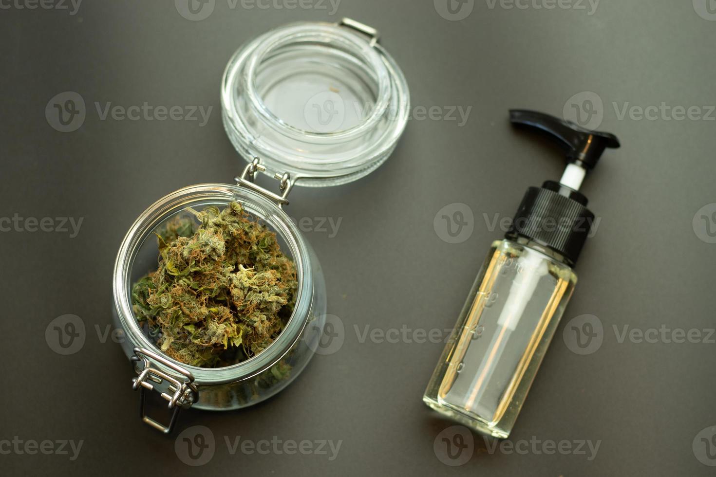 CBD herbal oil with cannabis buds in glass jar top view. Marijuana on black background. Weed business industry concept. Cannabidiol medical and recreational healthcare using photo
