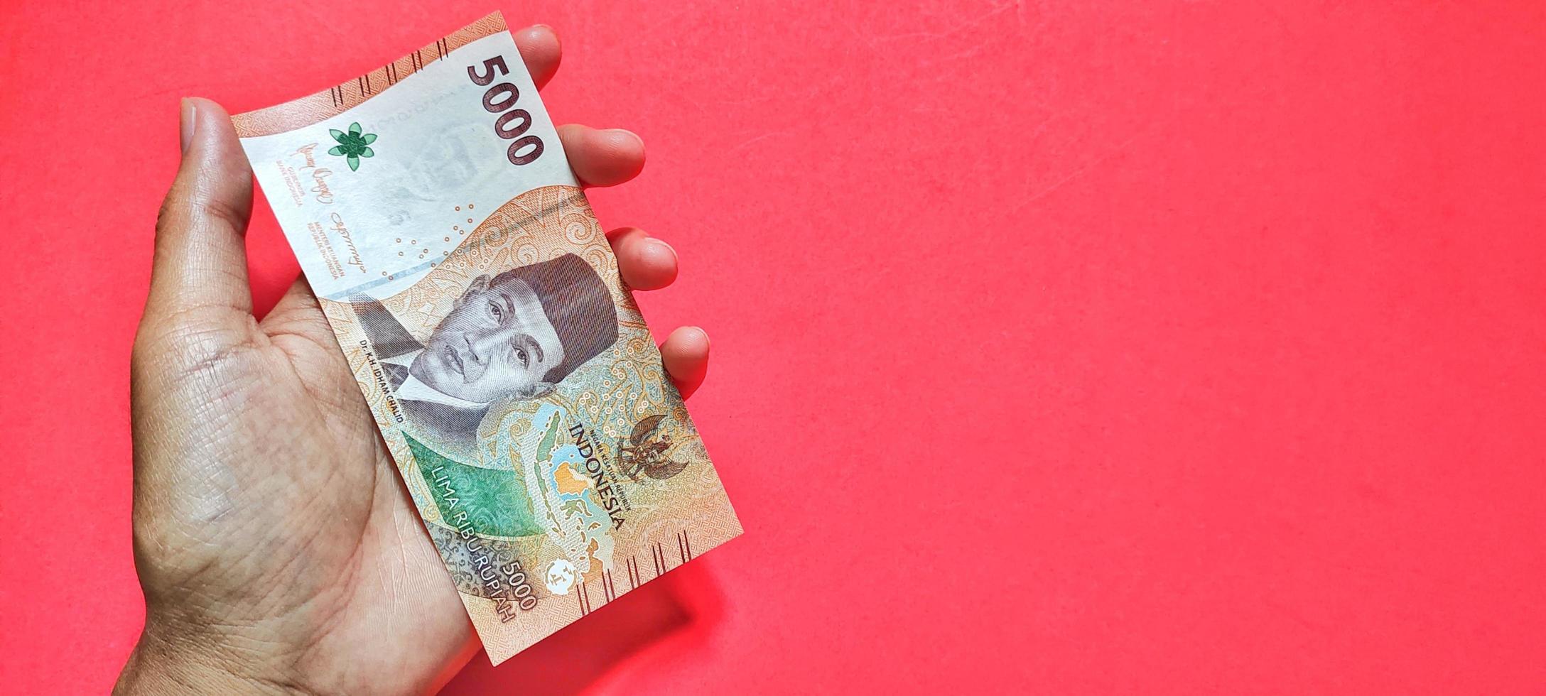 Man holding the latest edition of Indonesian 5000 rupiah banknotes photo