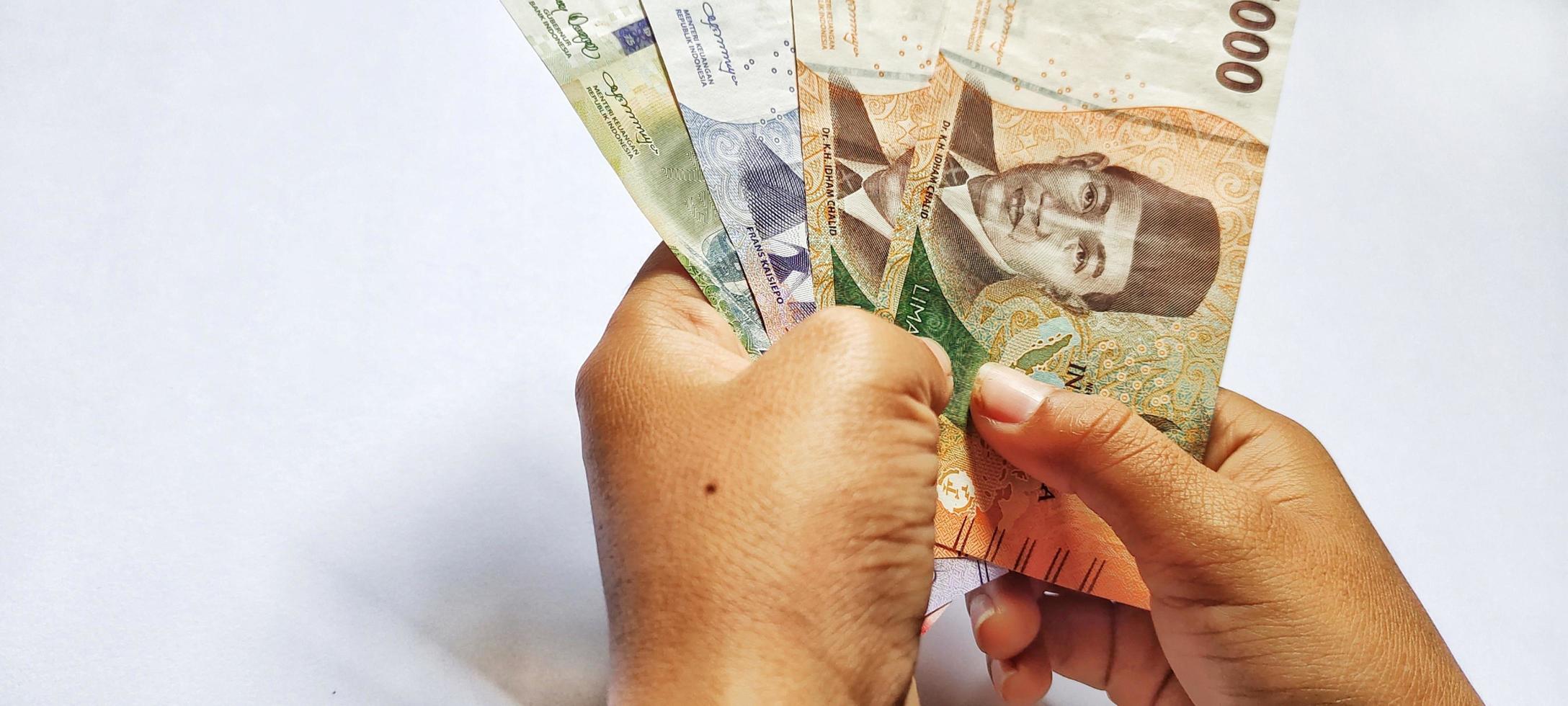 Man holding new money rupiah indonesia latest edition. Isolated on a white background photo