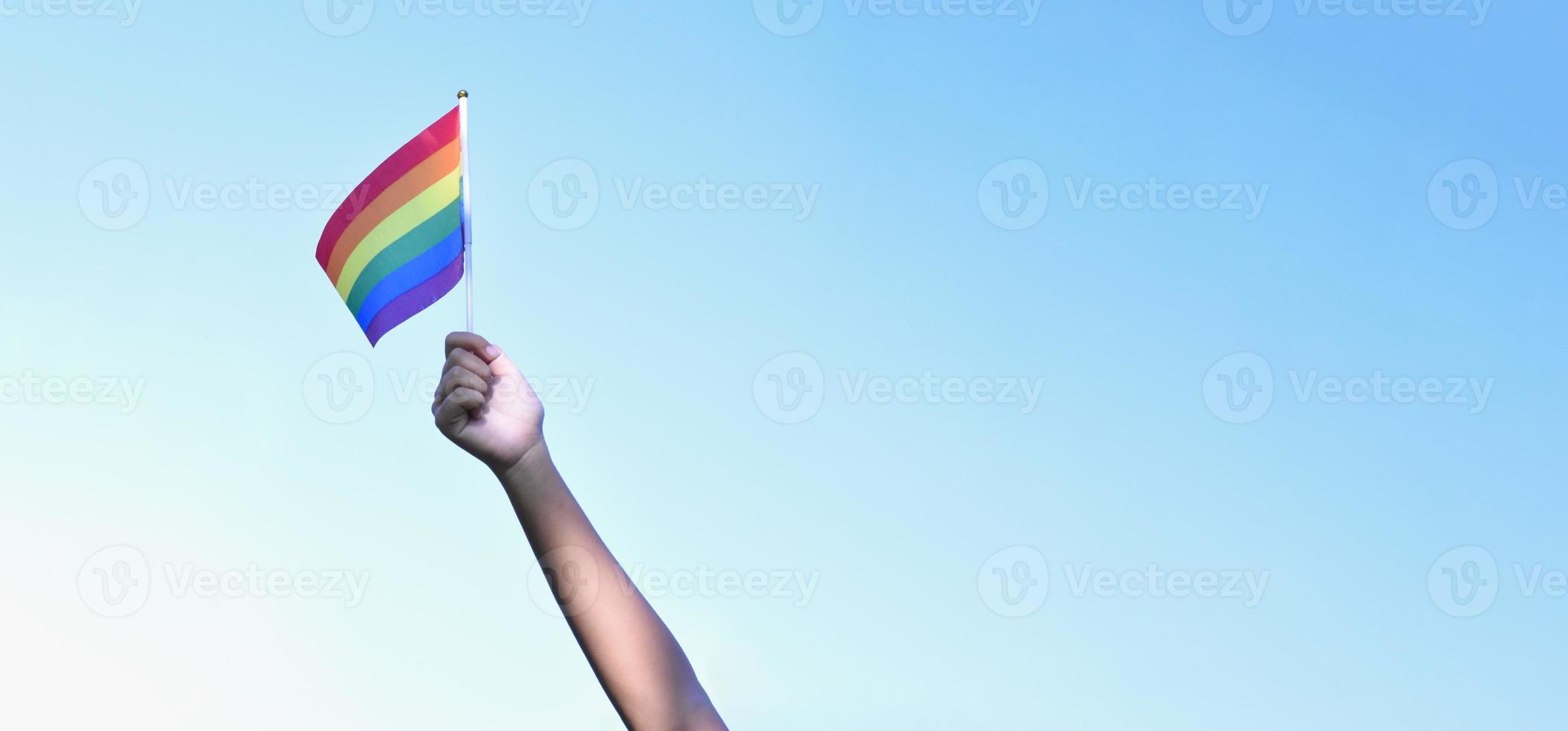 Rainbow flag faising against bluesky, copy space, soft focus, concept for LGBT celebrations in pride month, june, around the world. photo