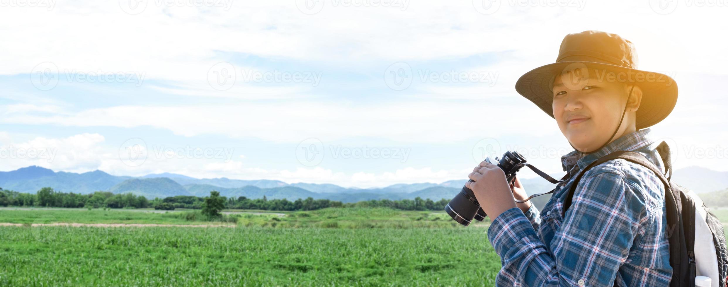 Asian boys using binoculars to watch birds on trees and fish in river in local national park during summer camp, idea for learning creatures and wildlife animals and insects outside the classroom. photo