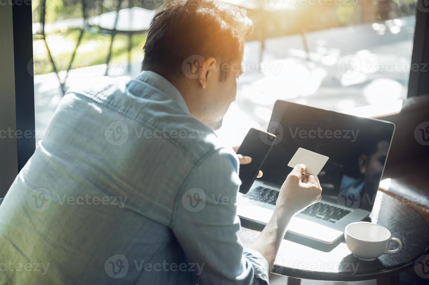 Young asian man holding credit card and using laptop online payment, online shopping concept with credit card in cafe photo