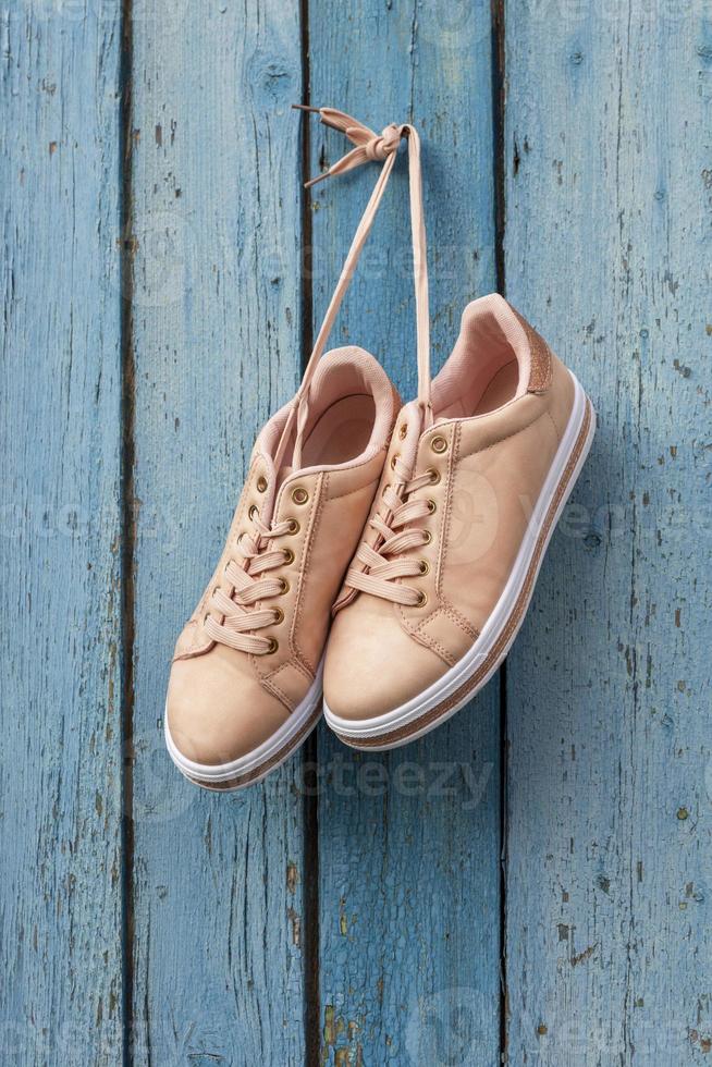 pair of beige female sports shoes hanging photo