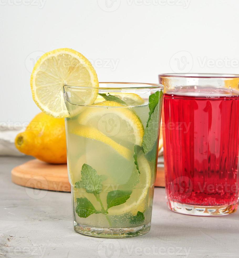 limonada con limones, hojas de menta, lima en un vaso y limonada de frutos rojos foto