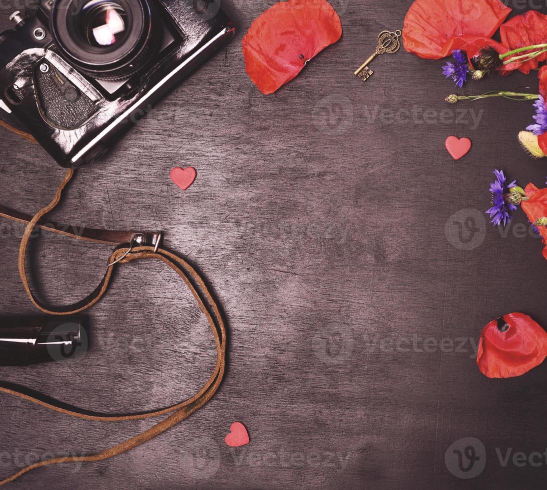 old vintage photo camera and bouquet of red poppies