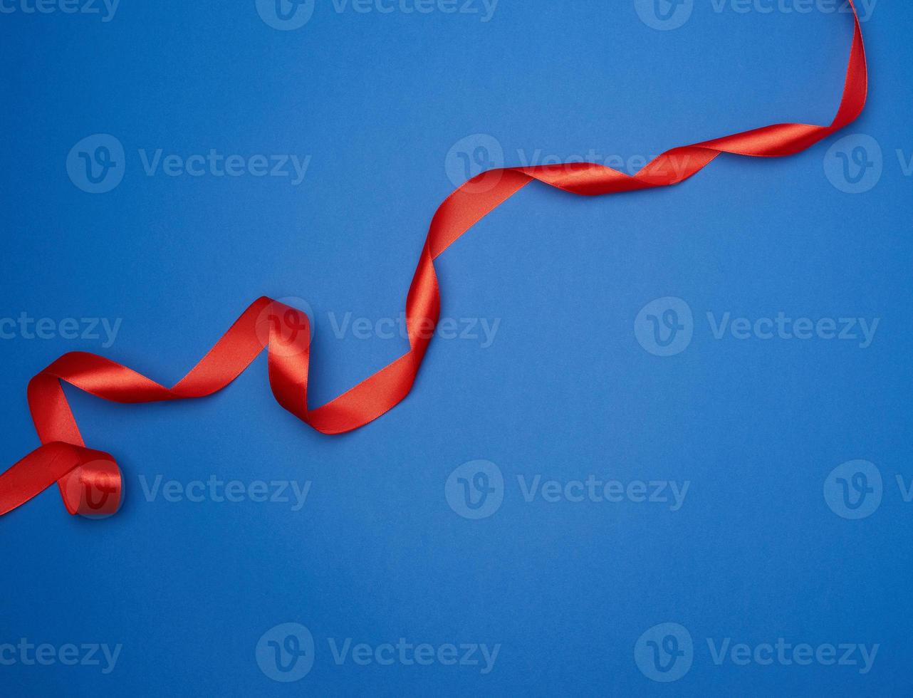 red silk thin ribbon twisted on a blue background, trendy classic color photo