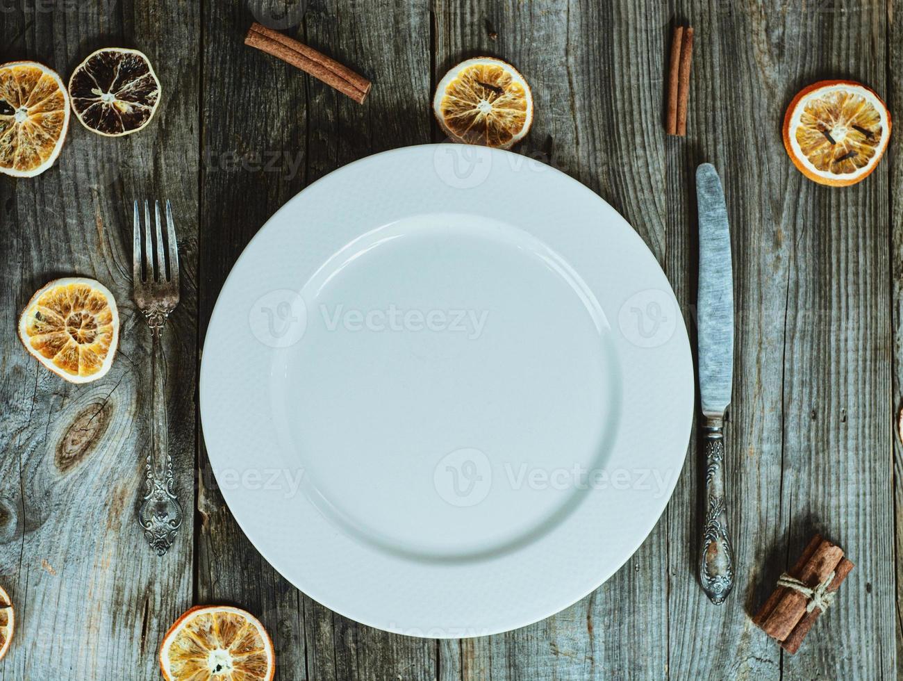 Empty white plate with cutlery, decoration dry slices of citrus fruits photo