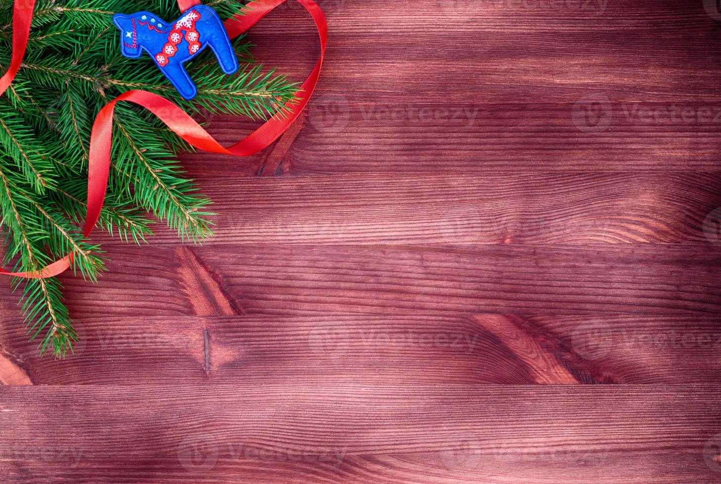 Green branch decorated with red ribbon on a wooden surface photo