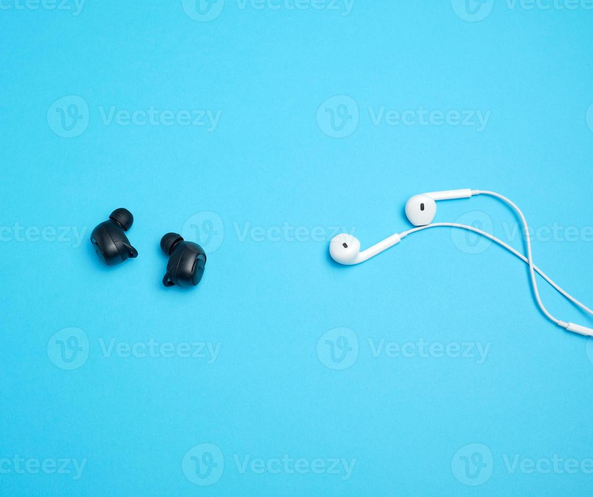 black wireless and white earphones with wire on a blue background photo