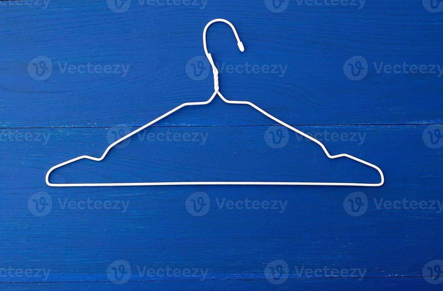 thin white metal hanger on a blue wooden background photo