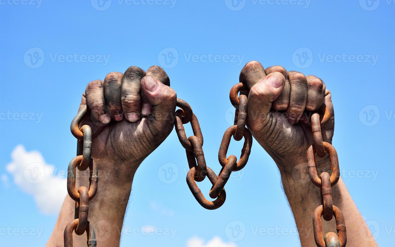 Two male hands holding a rusty metal chain photo