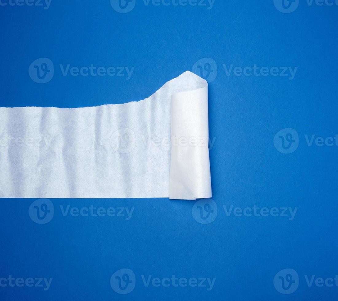 torn and twisted piece of white paper on a blue background photo