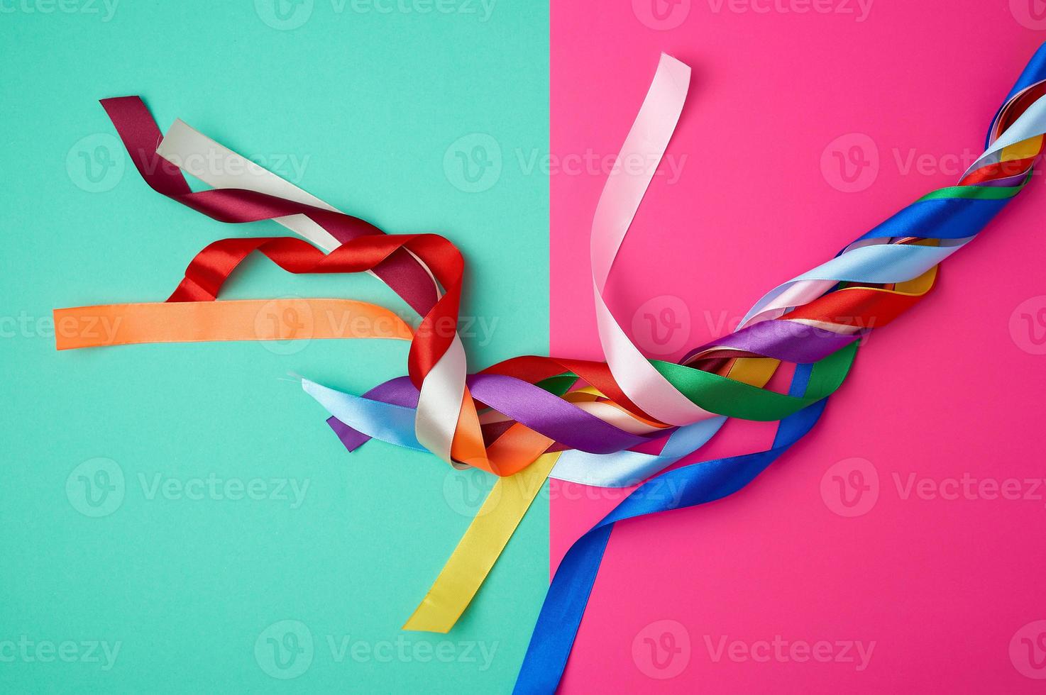 many silk multi-colored ribbons on a colored background photo