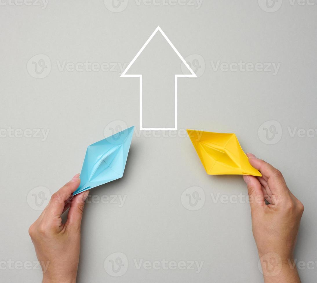 Two yellow-blue paper boats in female palms on a gray background. Ukraine support concept photo